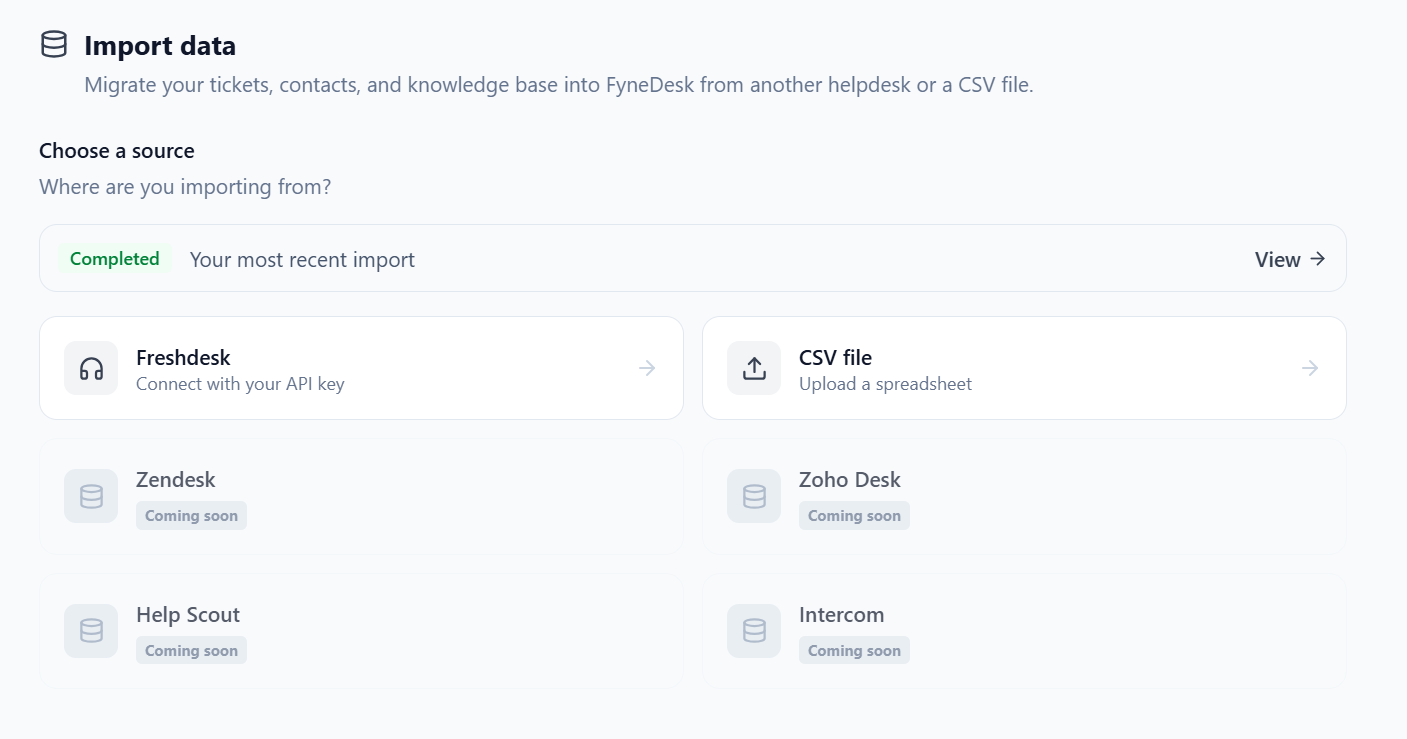 La pantalla de Importar datos con el paso Elegir una fuente. Freshdesk (Conectar con tu clave API) y archivo CSV (Subir una hoja de cálculo) están disponibles, mientras que Zendesk, Zoho Desk, Help Scout e Intercom se muestran atenuados con una etiqueta de Próximamente. Un banner en la parte superior enlaza con tu importación completada más reciente.